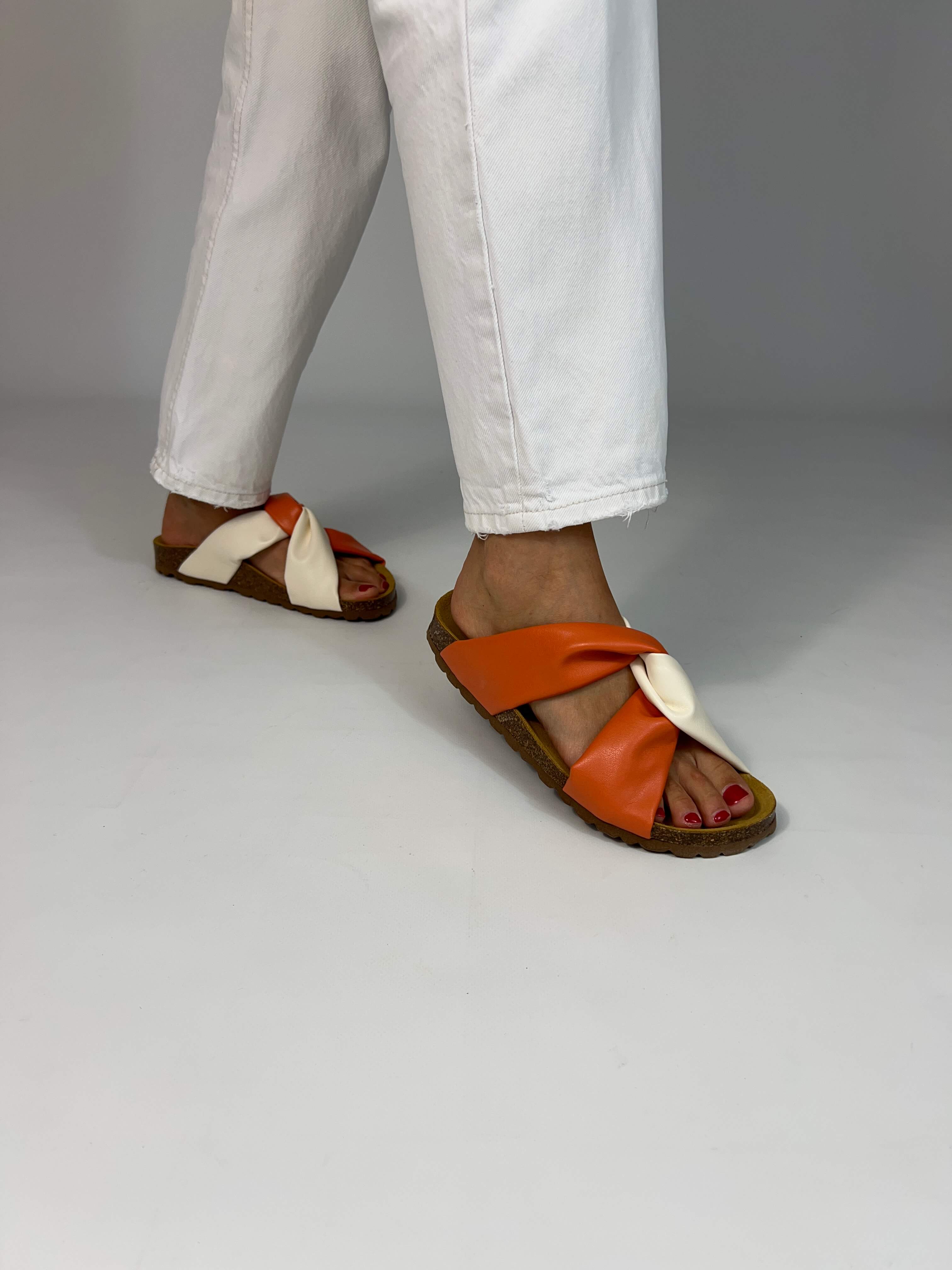 Momoc Calpe orange cream sandals worn side view walking white trousers central knot detail handmade | Momoc Shoes