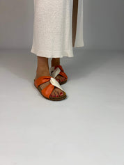 Momoc Calpe orange terracotta sandals worn side view white skirt cross strap design | Momoc Shoes Spain