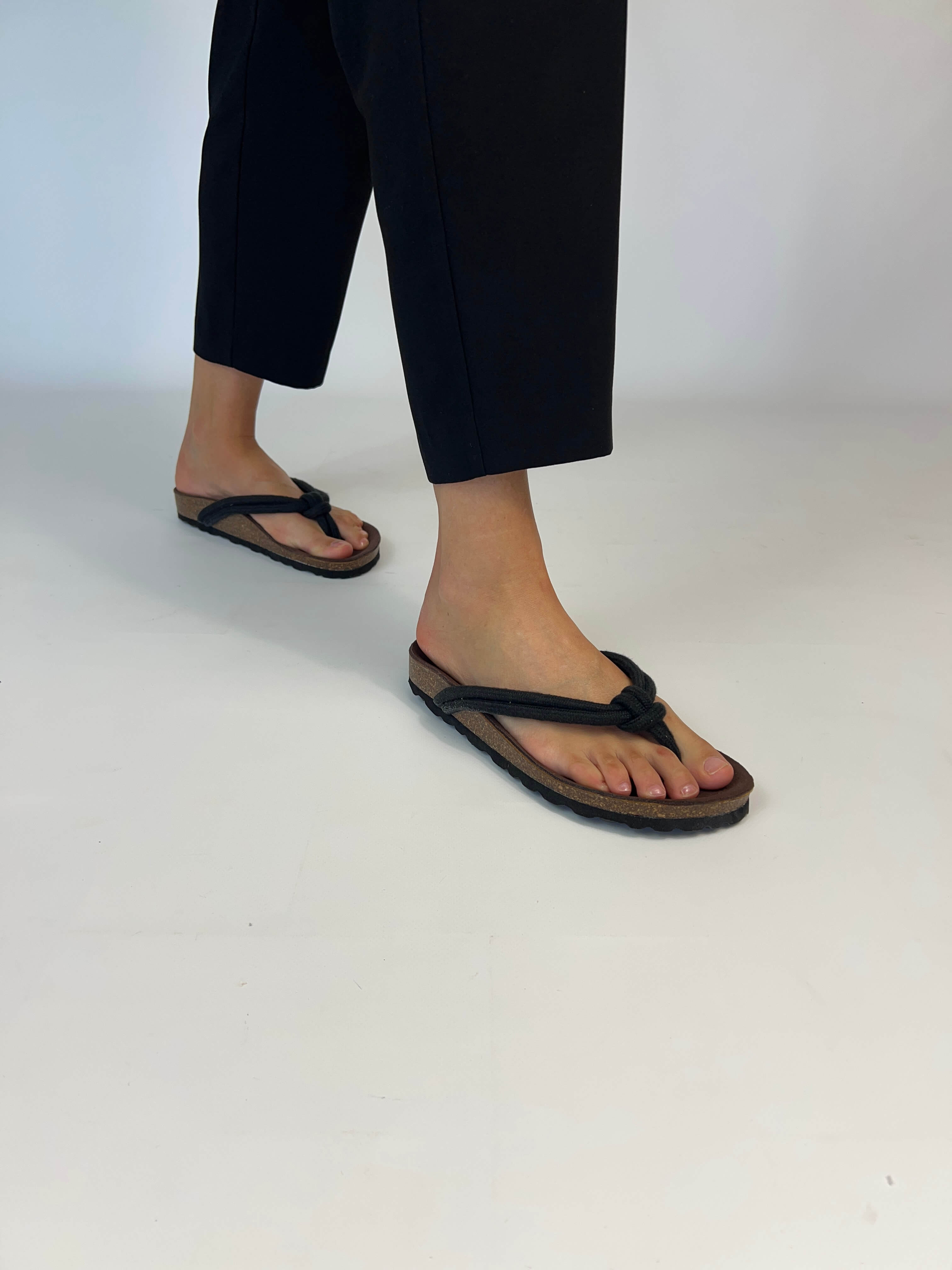 Momoc Javea black rope sandal worn side view black trousers white background sustainable | Momoc Shoes