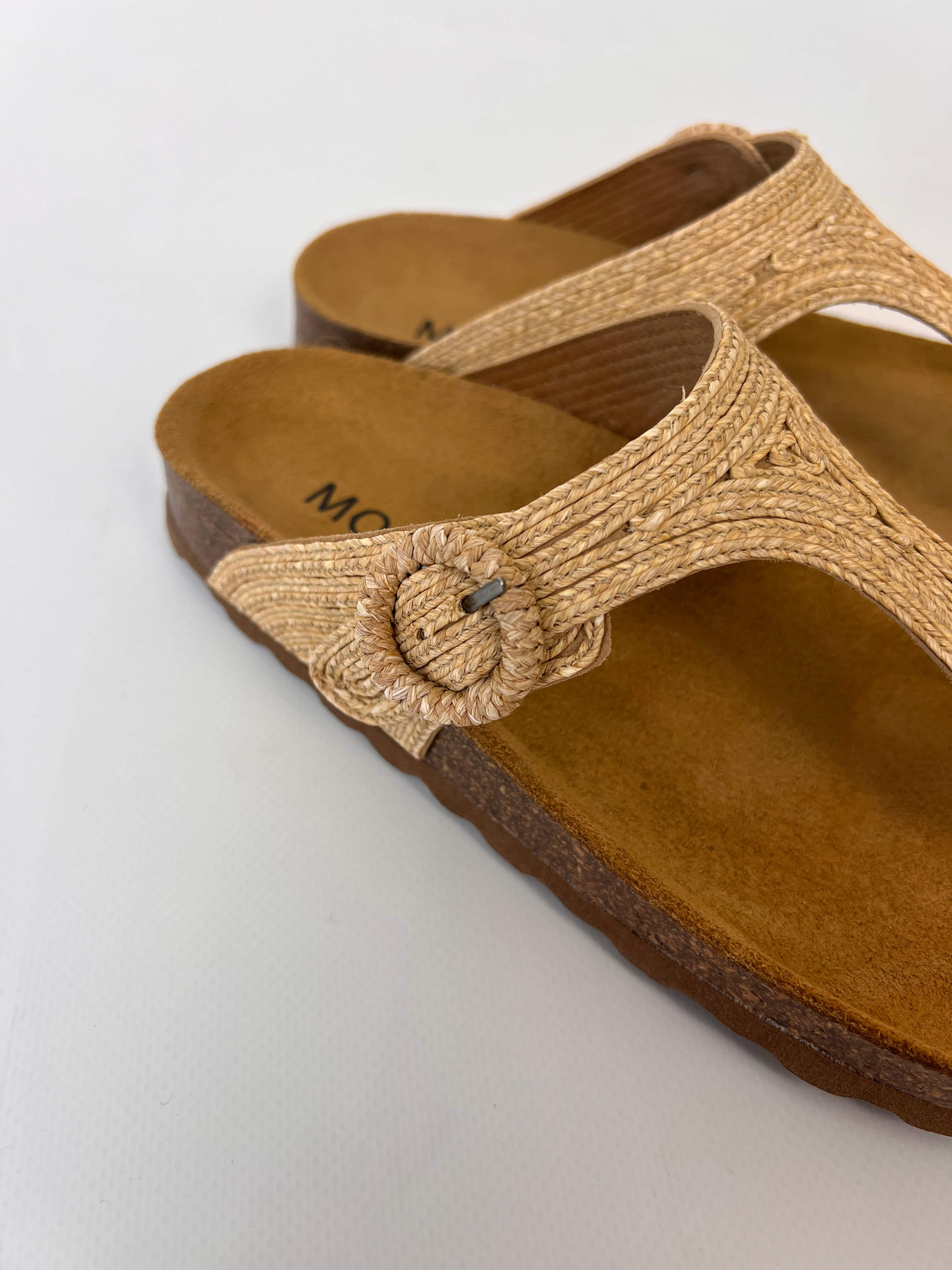 Momoc Altea natural raffia sandal close up hand adjusting raffia buckle detail Spain | Momoc Shoes Spain
