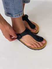 Momoc Altea black raffia sandal close up hand adjusting raffia buckle detail Spain | Momoc Shoes