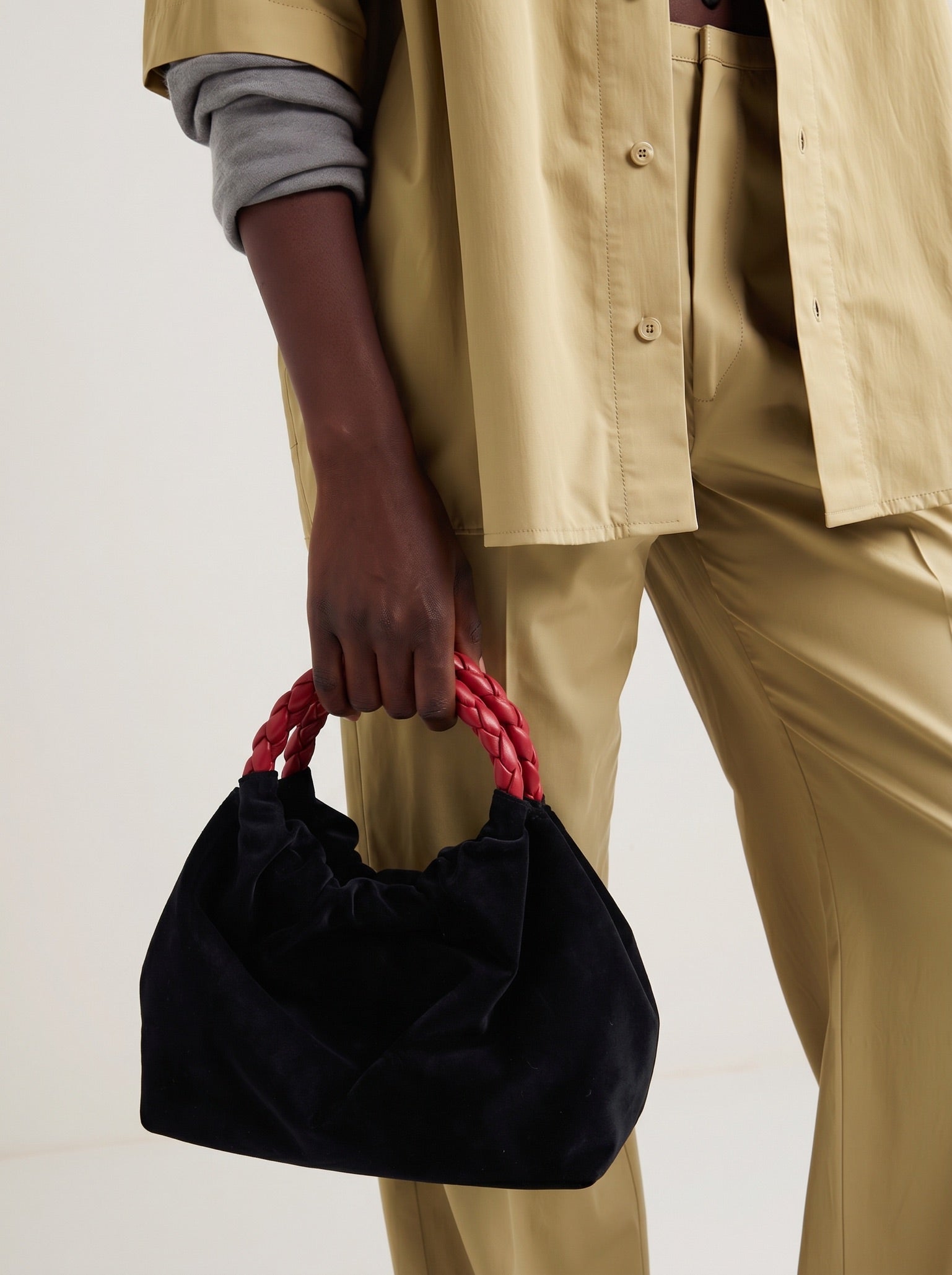 Momoc Pigalle black velvet bag burgundy handle held by hand beige outfit side view | Momoc Shoes
